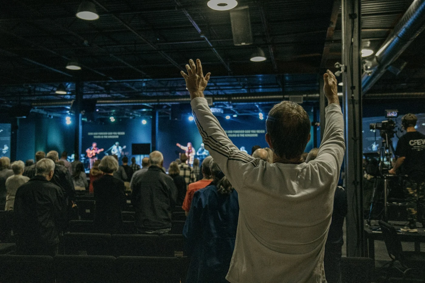 People gathered in worship, with raised hands in the foreground